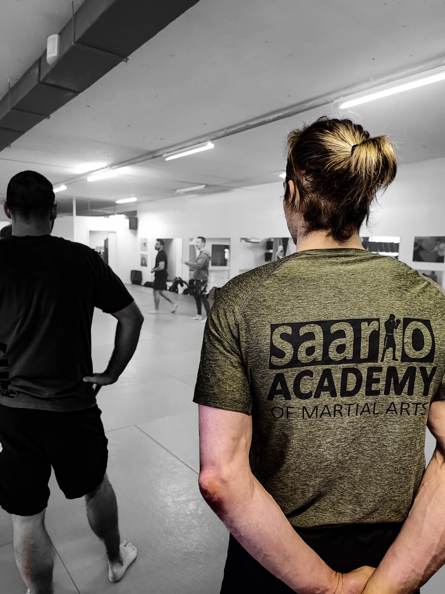 Herb Saario Academy na plecach koszulki treningowej, w tle trenująca grupa